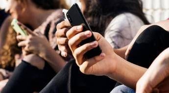 Close-up of several people holding smartphones in a crowd.