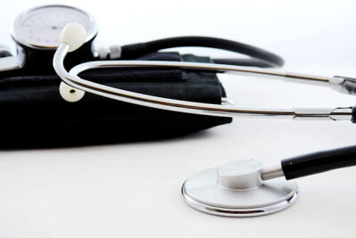 Stethoscope lying across a blood pressure cuff with a gauge in the background, ready for a medical examination.