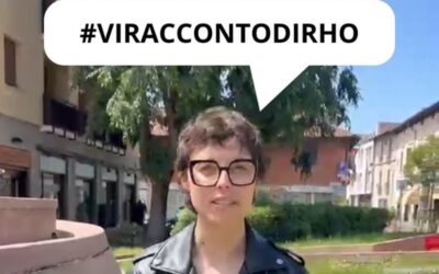 Person with short hair and glasses speaks outdoors, wearing a black leather jacket; a speech bubble above reads '#VIRACCONTODIRHO'.