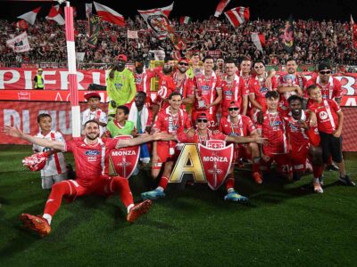 Monza football team celebrating with trophy and fans in the stadium stands